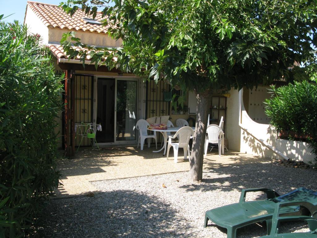 eine Terrasse mit einem Tisch und Stühlen unter einem Baum in der Unterkunft Vias Plage - Maison de vacances in Vias
