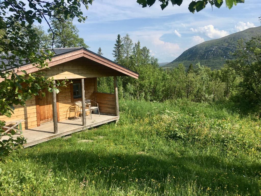 eine Hütte mit einem Deck auf einem Grasfeld in der Unterkunft Fjällhalsen Cottages in Fjällhalsen