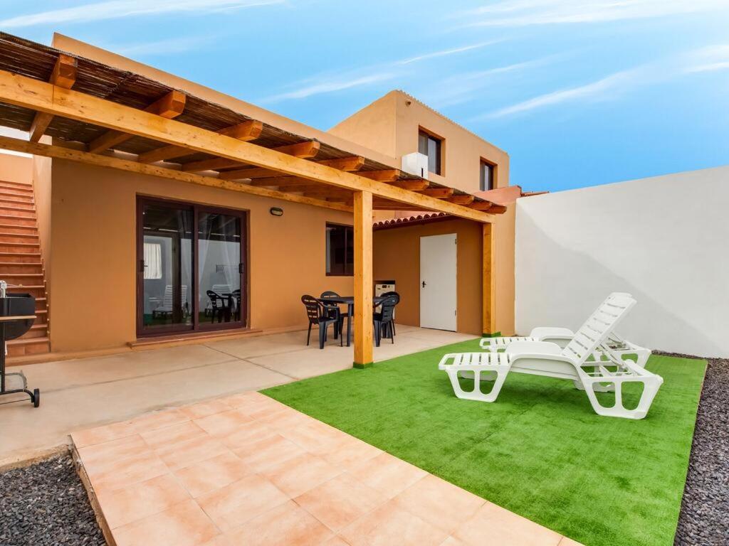 a patio with a table and chairs on the grass at Casa Aloe in Corralejo