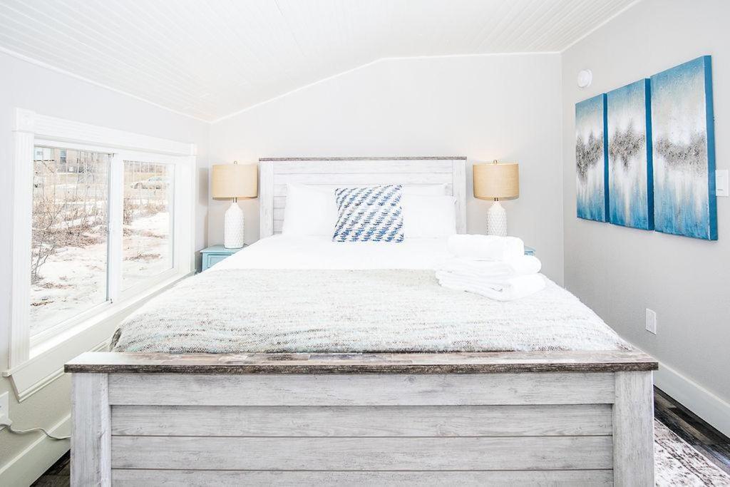 a white bedroom with a large bed with two lamps at Couples Getaway - Walk to UNC - Free Cruiser Bikes in Greeley