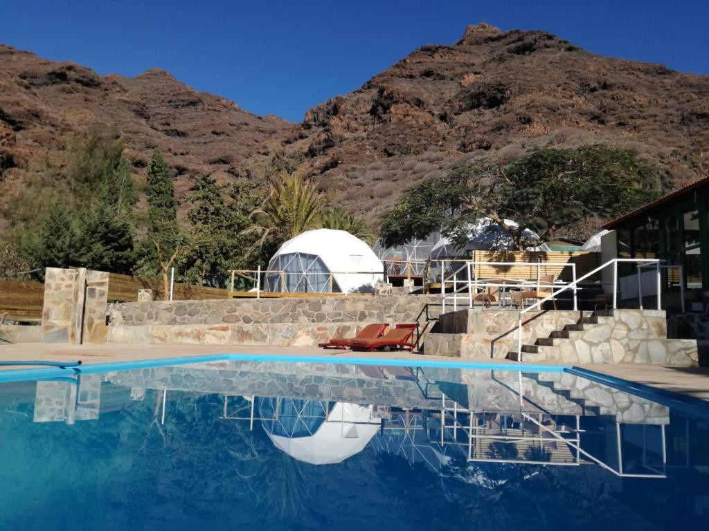 una piscina con sillas y una montaña en Blue Ocean Camp - Tasartico, en Tasartico