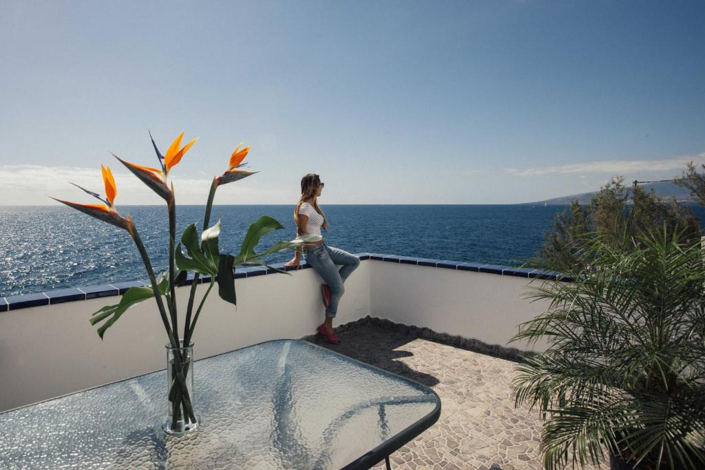 a woman sitting on a balcony overlooking the ocean at Canary casita next to the Atlantic Ocean in Radazul