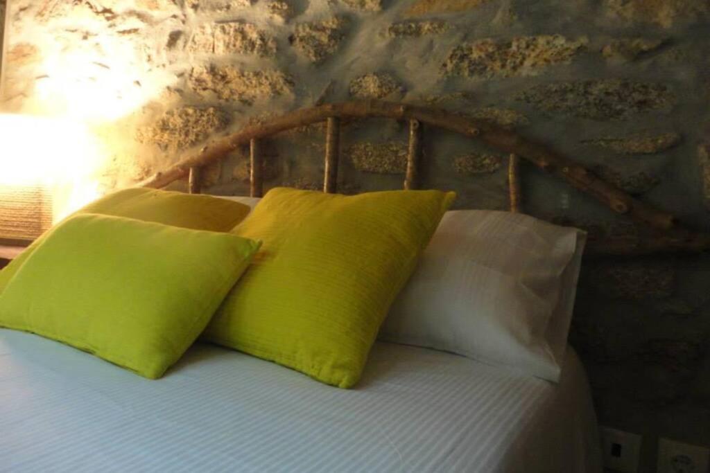 a bed with two lime green pillows on it at Casa do Palheiro in Miranda do Douro