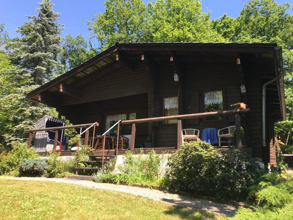 a log cabin with a porch and chairs in the yard at Immerkopf in Wiehl