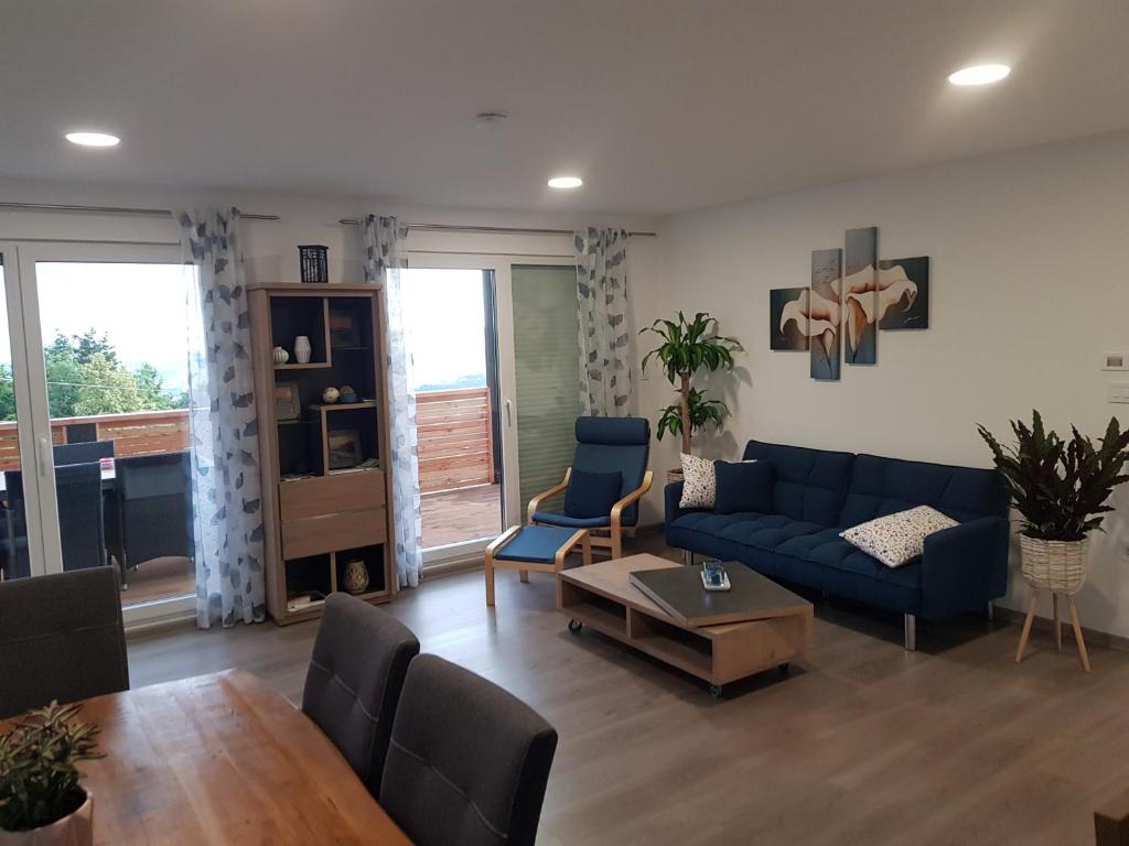 un soggiorno con un divano blu e un tavolo di Ferienwohnung Weizblick a Weiz