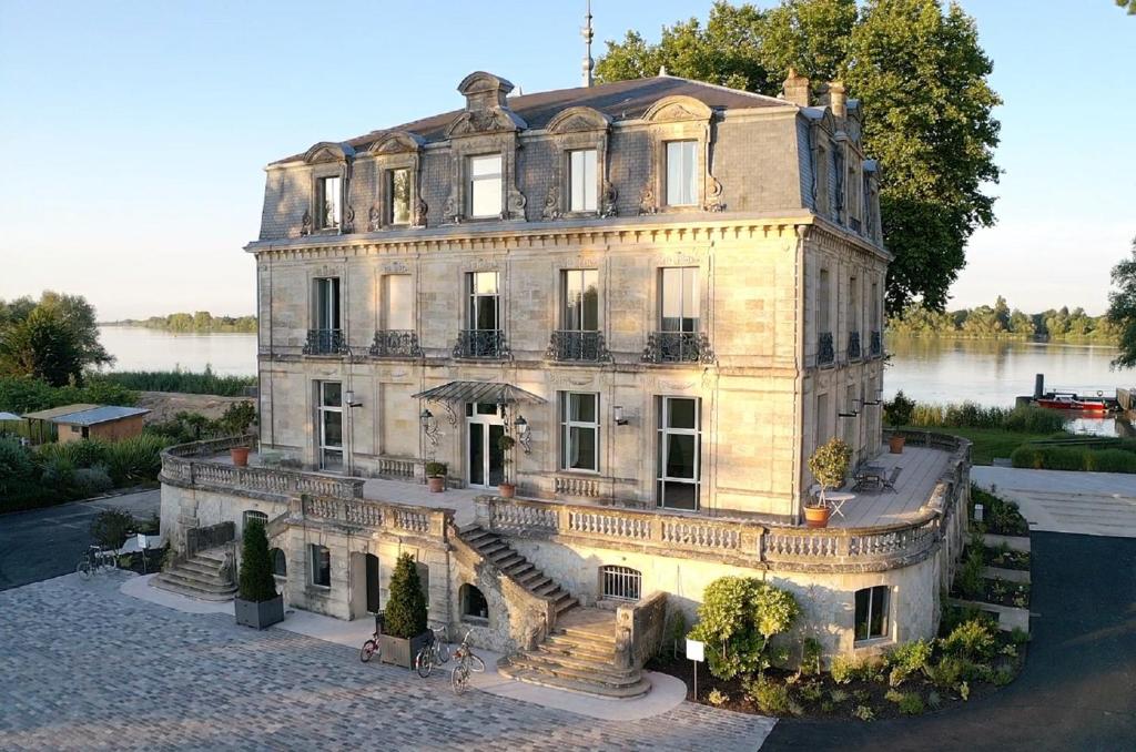 uma casa antiga com escadas em frente a um lago em Château Grattequina Hôtel em Blanquefort