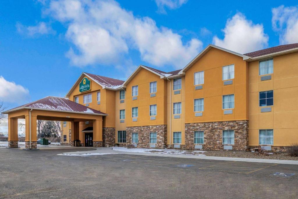 La Quinta Inn & Suites Casino and Bar by Wyndham Glendive في غلينديف: مبنى برتقالي كبير مع موقف للسيارات