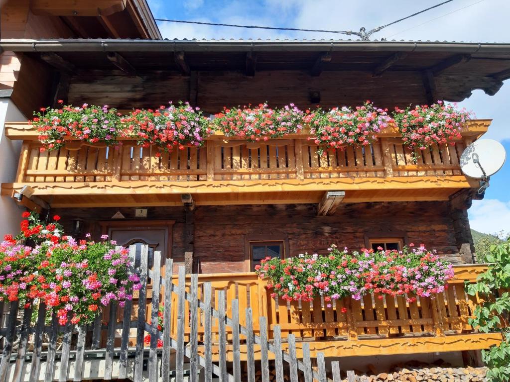 a wooden house with flowers on a balcony at Ferienhaus Grofn in Matrei in Osttirol
