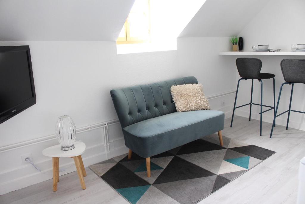 a living room with a blue chair and a tv at Studio plein coeur d'Auxerre in Auxerre