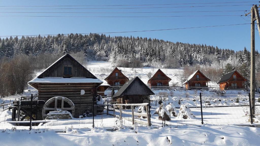 eine Gruppe von Blockhütten im Schnee in der Unterkunft Domki Karczma Zbójnicka in Wiśniowa