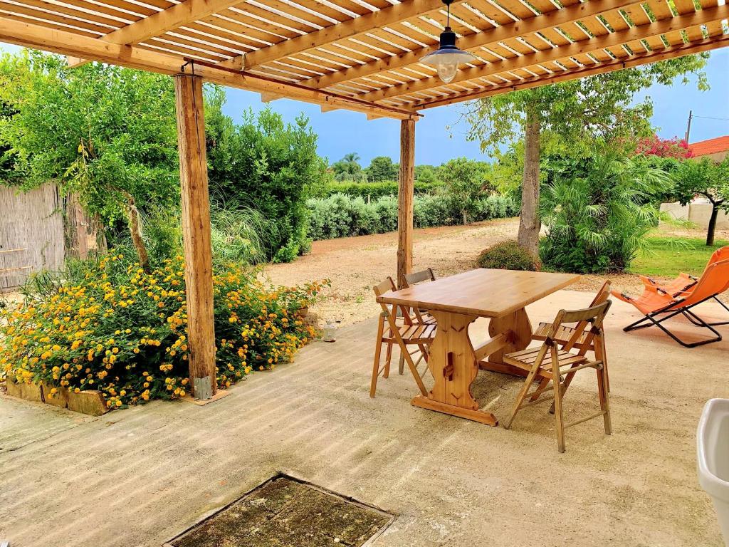 un tavolo e sedie in legno sotto un pergolato di legno di Villa Siciliana con piscina "Dal PICCIOTTO" a Marsala