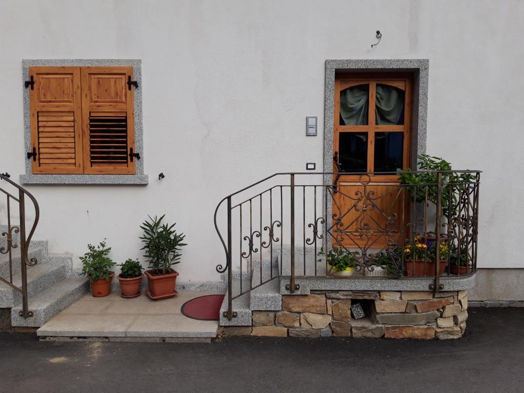 a building with a door and a balcony with potted plants at La casetta di Giulia in Commezzadura