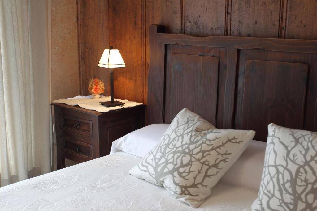1 dormitorio con 1 cama con cabecero de madera y lámpara en El Mirador del Alberche III, en Navaluenga