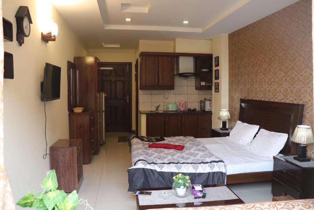 a bedroom with a large bed and a kitchen at Cozy Studio Apartment In Bahria town in Rawalpindi