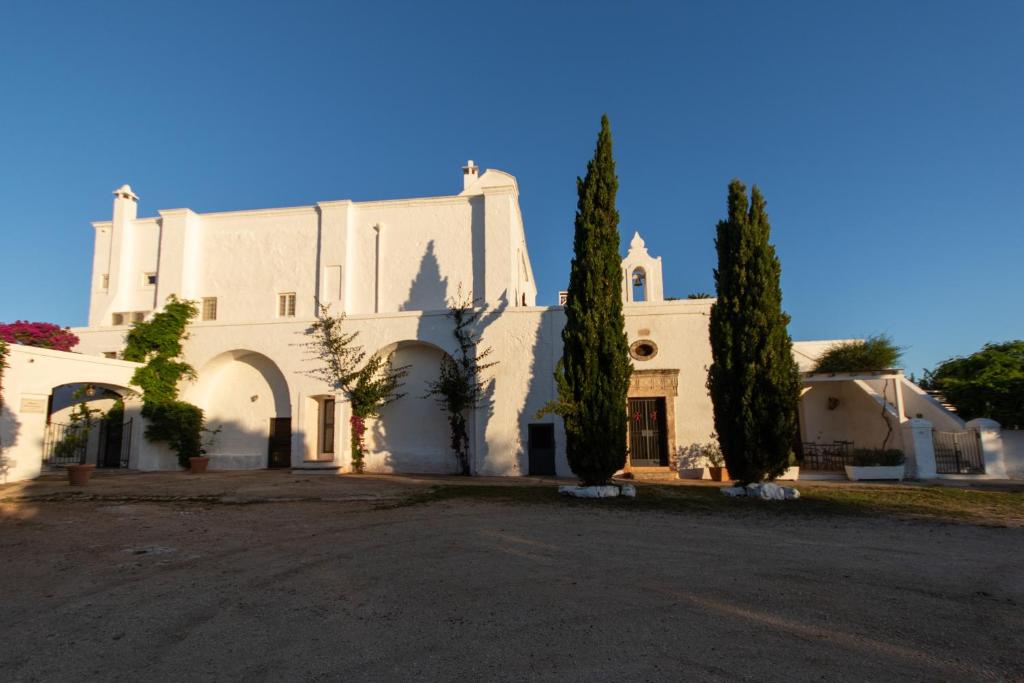 a large white building with trees in front of it at Masseria Parco di Castro in Montalbano