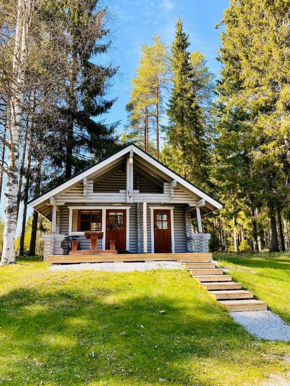 a small house with a porch in the grass at Huhtaniemen Mökkikylä in Veteli