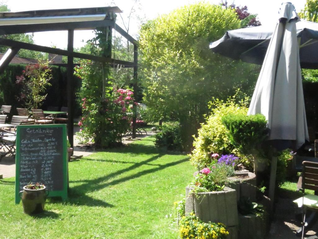 a garden with a sign and an umbrella and flowers at Gast-&amp; Logierhaus Am Rheinsberger See in Rheinsberg