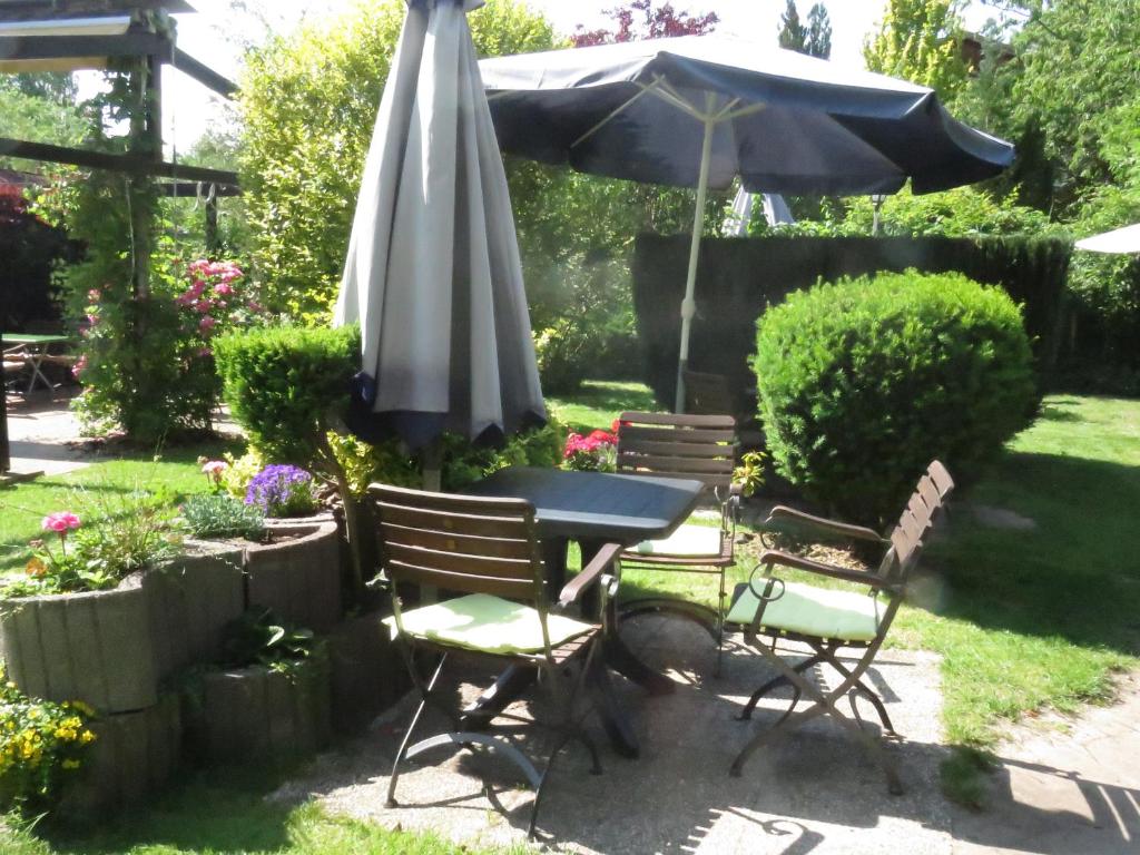 a table and chairs with an umbrella in a garden at Gast-&amp; Logierhaus Am Rheinsberger See in Rheinsberg