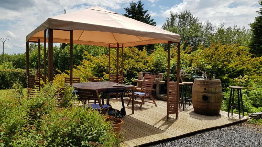 une terrasse en bois avec une table et un parasol dans l'établissement Les Glycines, à Gouvy