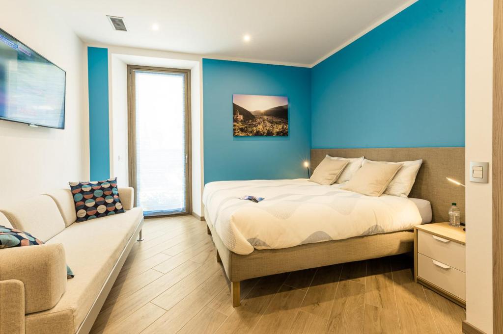 1 dormitorio con paredes azules, 1 cama y 1 sofá en Le Rondini, en Tirano