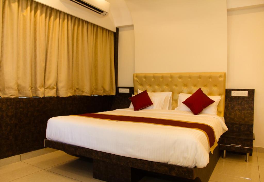 a bedroom with a large bed with red pillows at GOLDEN AMULYA REST WINGS in Yelahanka