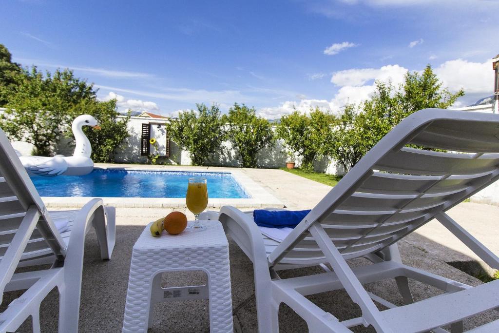 Vacation house Vila Guma Rastani Mostar في موستار: زوج من الكراسي وطاولة وبجعة بجانب مسبح