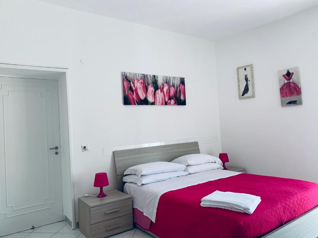 um quarto branco com uma cama com um cobertor vermelho em Casa Sofia em Sorrento
