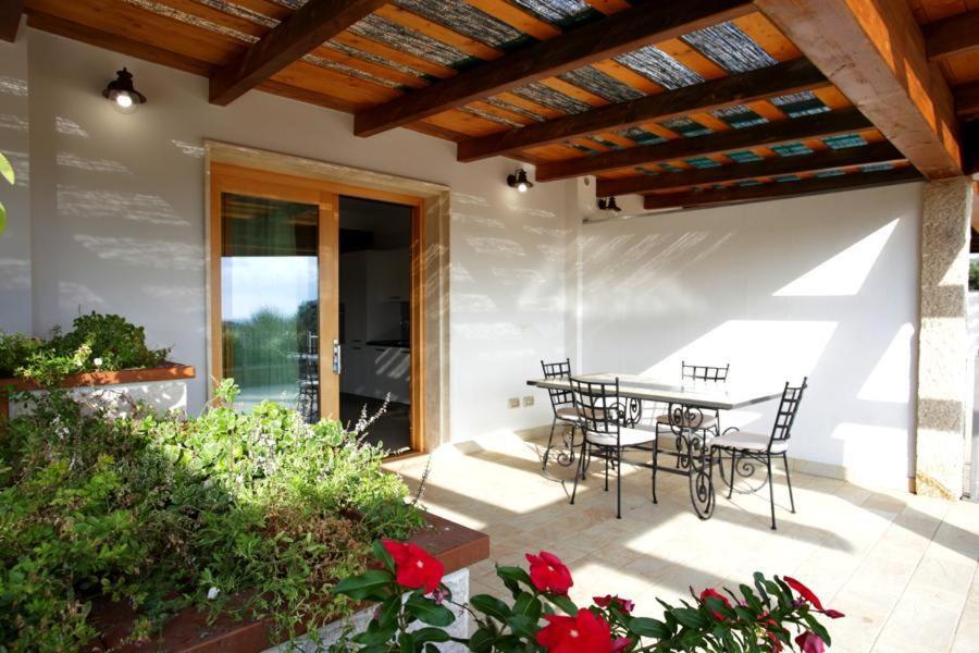 een patio met een tafel, stoelen en bloemen bij Cala Azul Residence B&B in Alghero