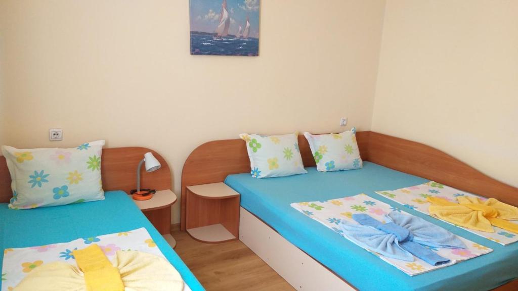 two beds in a small room with blue at Ivanovi Guest House in Primorsko