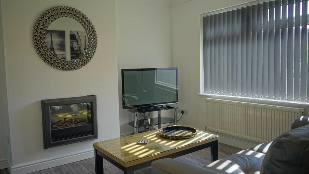 a living room with a tv and a coffee table at Palm House in Widnes