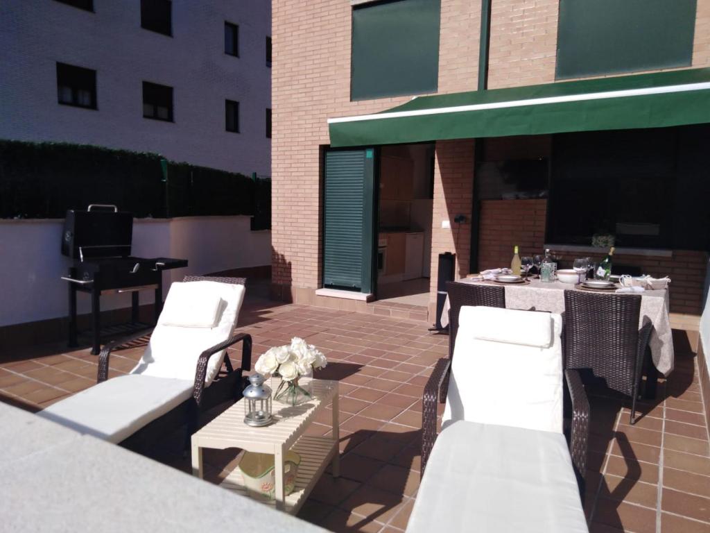 a patio with white chairs and tables and a building at DavidSara in Llanes