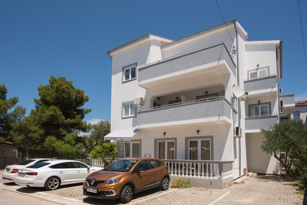 una casa blanca con dos coches aparcados delante de ella en Apartments Lovrić, en Vodice