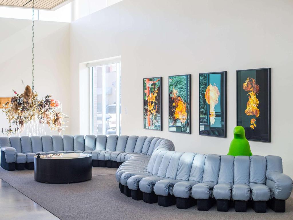 a living room with blue leather couches and a green person at 21c Museum Hotel Bentonville - MGallery in Bentonville