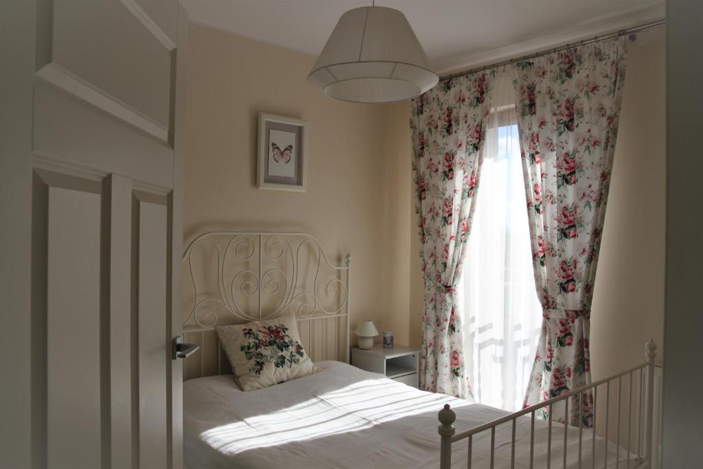 1 dormitorio con 1 cama y una ventana con flores en Apartament Motyl en Władysławowo
