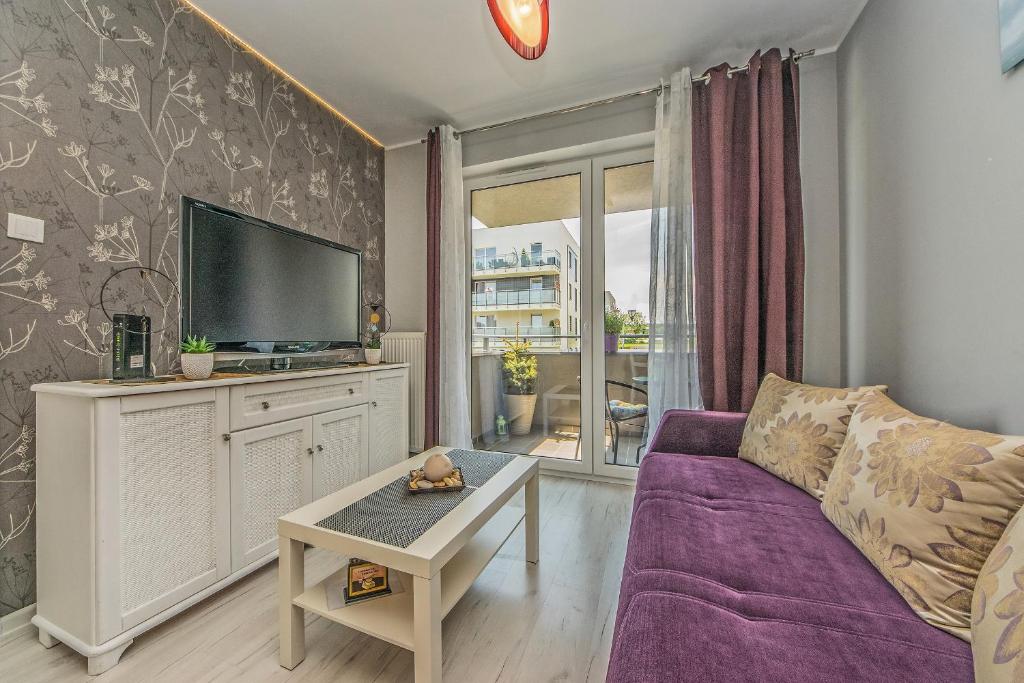 a living room with a purple couch and a tv at Apartament LUX in Pruszcz Gdański