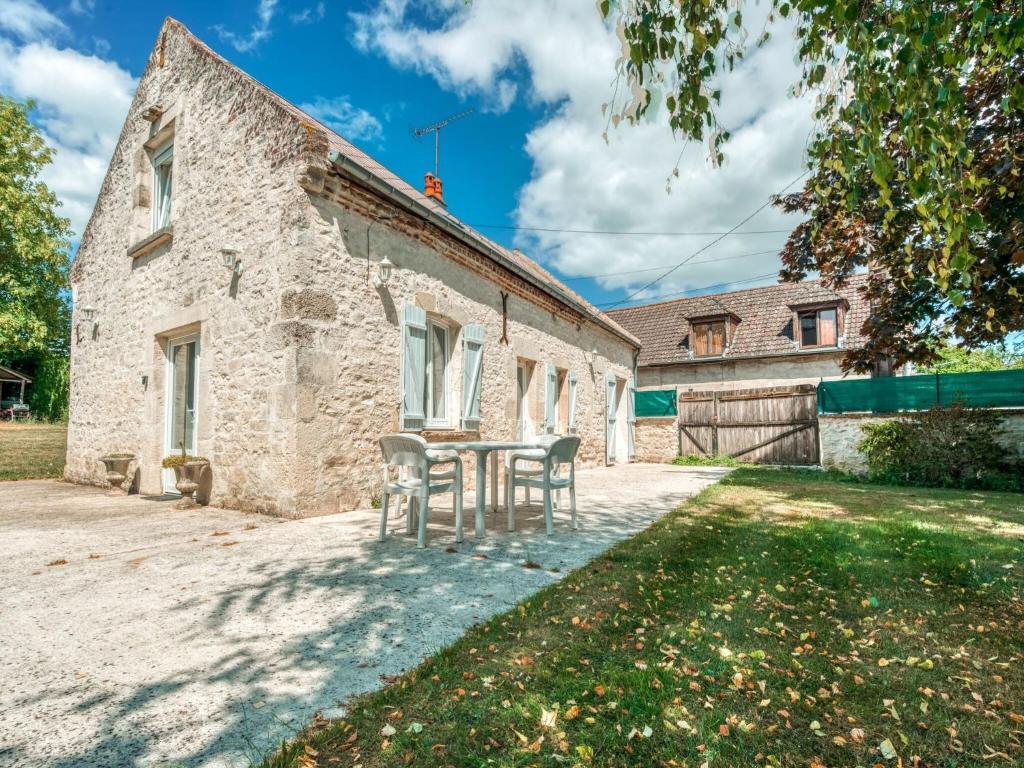 Cozy Farm House in Boncourt with Barbeque في Sainte-Preuve: منزل حجري قديم مع طاولة وكراسي
