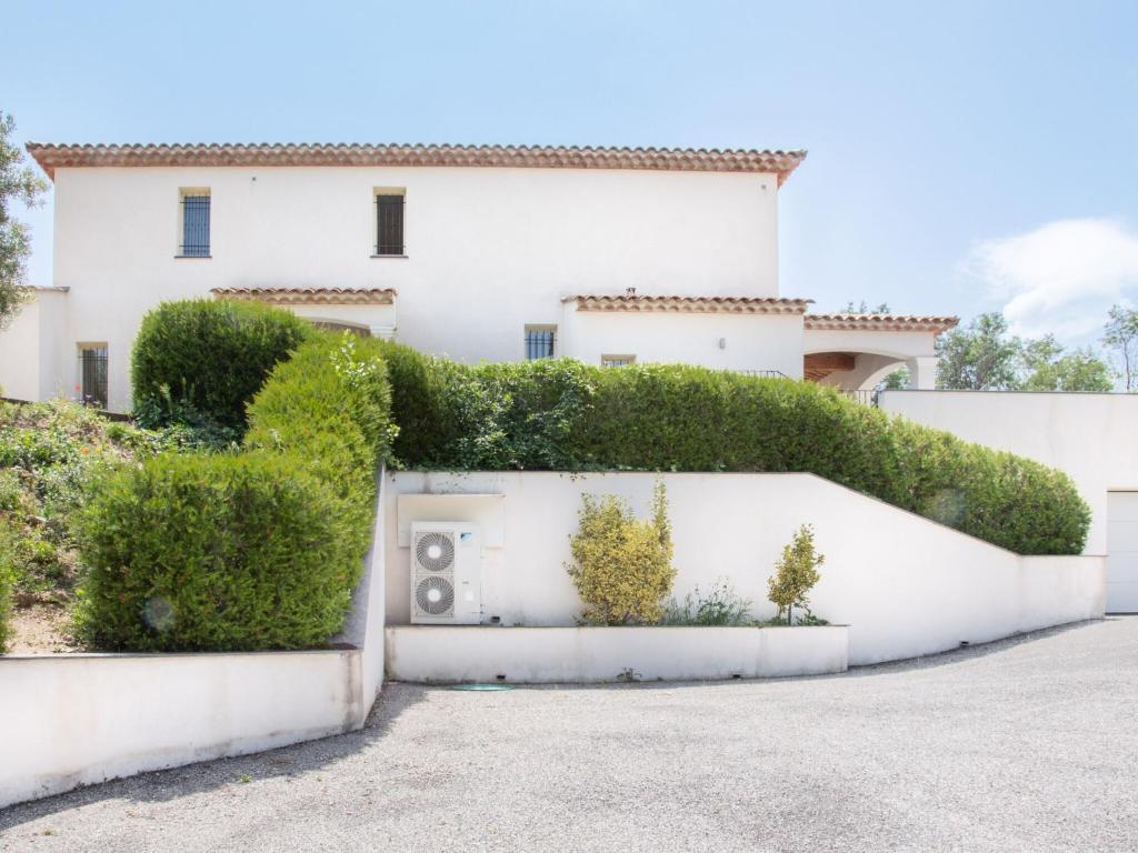 a white house with a hedge on it at Cosy villa with private pool in Emponse