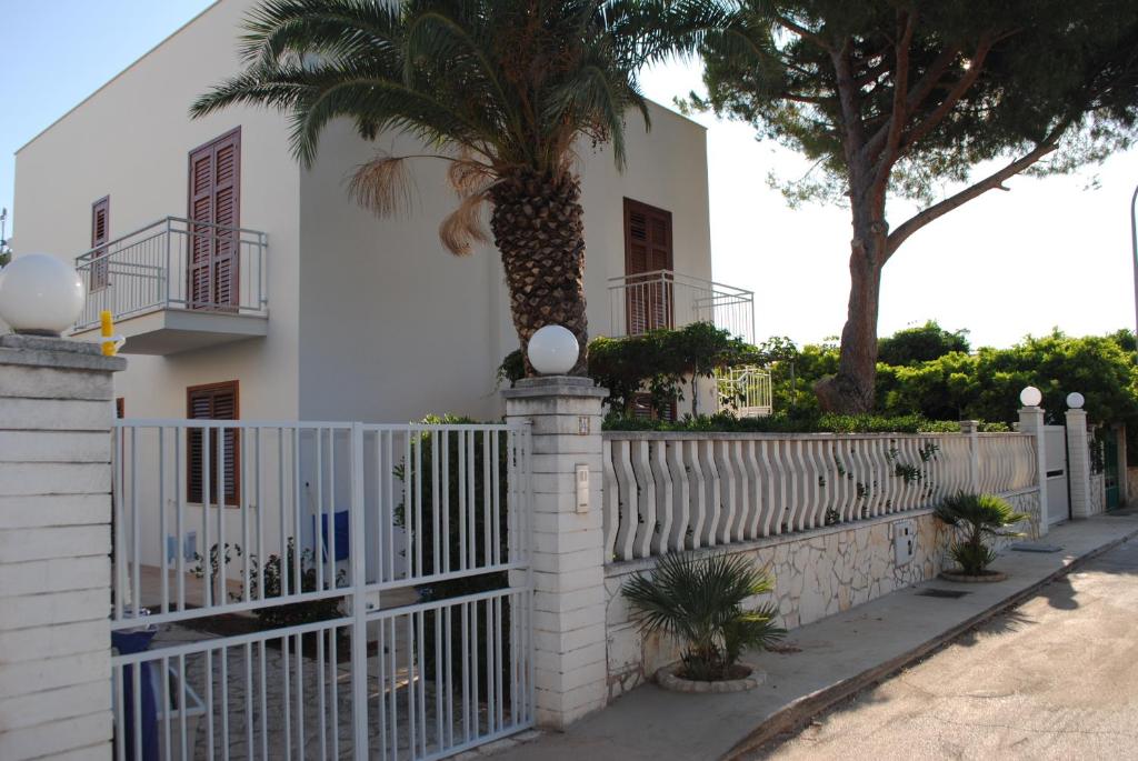 a white fence in front of a house with a palm tree at Villa Smeralda in San Vito lo Capo