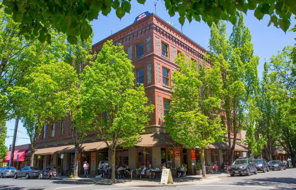 a red brick building on a street with trees at McMenamins Hotel Oregon in McMinnville