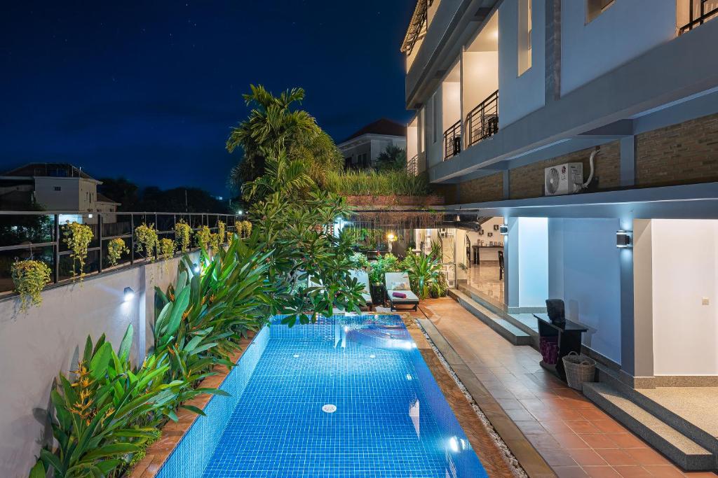 ein Schwimmbad an der Seite eines Gebäudes in der Nacht in der Unterkunft Villa Agati in Siem Reap