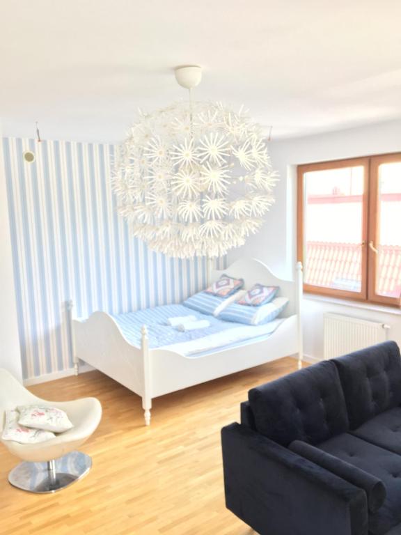 a living room with a bed and a chandelier at Ełk Blue Apartment przy promenadzie in Ełk
