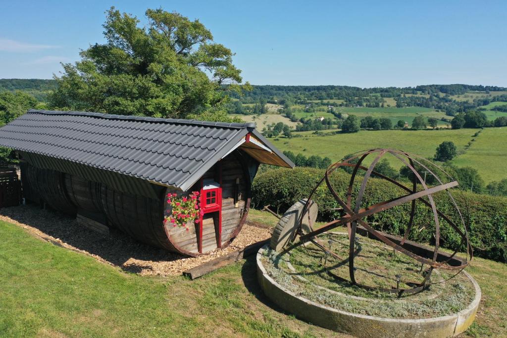 una casa pequeña y una gran rueda de agua en un campo en Hébergements Insolites dans tonneaux - Gite Le Coup de Foudre, en Vimoutiers