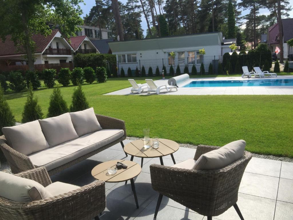 a patio with wicker chairs and tables and a pool at Pobierowo Dom z basenem Haus mit Schwimmbad in Pobierowo