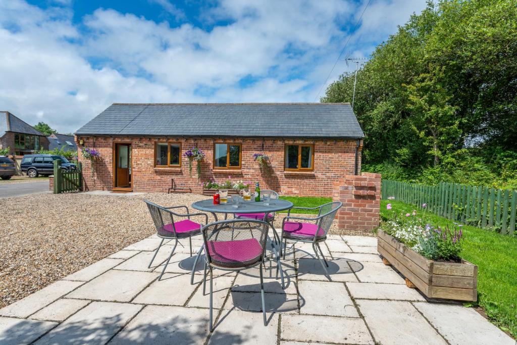 een patio met een tafel en stoelen voor een huis bij Nutley Farm in Winfrith Newburgh