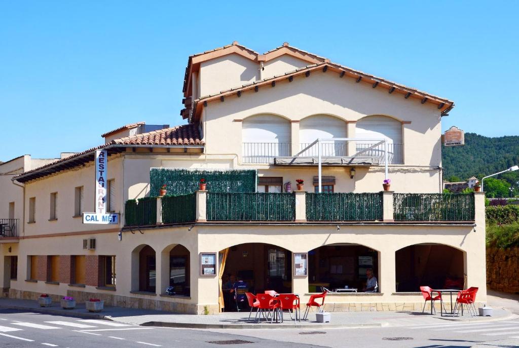 a building with red chairs in front of it at Casa Rural Cal Met in Sant Boi de Lluçanès