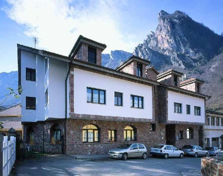 un gran edificio con coches estacionados frente a él en Hotel Casa Miño, en Pola de Somiedo