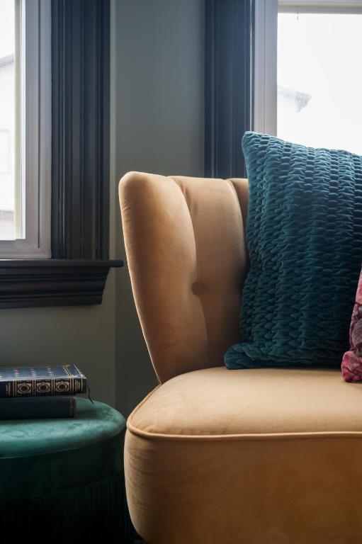 a brown chair with a blue pillow in a room at Slaymaker & Nichols Gastro House & Inn in Charlottetown