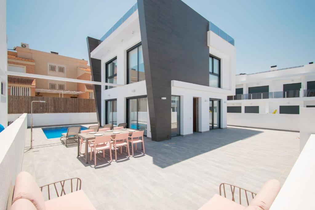 205 Luxury Gran Villa - Alicante Holiday في غران ألاكانت: فناء به طاولة وكراسي أمام مبنى