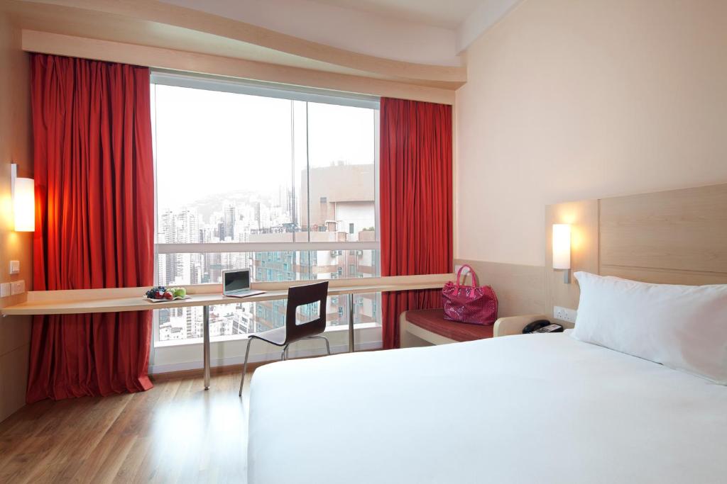 a hotel room with a bed and a desk and a window at Ibis Hong Kong Central & Sheung Wan in Hong Kong
