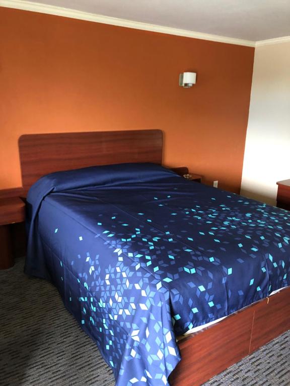 a bed in a room with a blue comforter at Skyview Motor Inn in Johnston